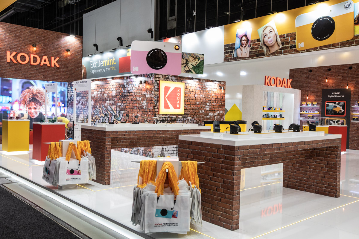 Kodak at IFA Berlin 2018 — Stand design Wide view of the Kodak exhibition stand with brick-effect walls and product counters at IFA Berlin 2018