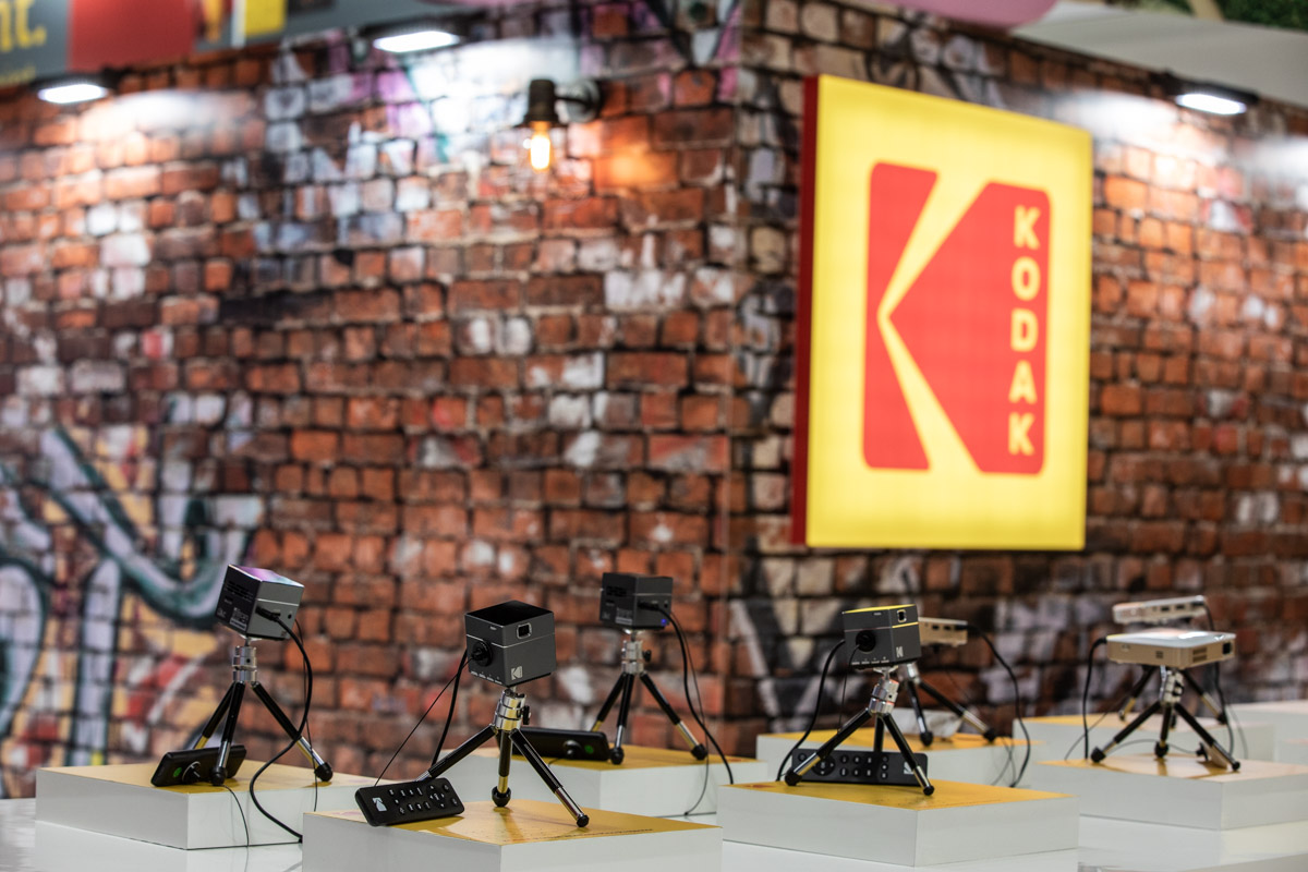 Kodak at IFA Berlin 2018 — Product display Camera accessories and small tripods displayed against a brick-effect Kodak backdrop at IFA Berlin 2018