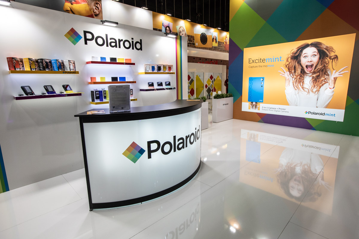 Polaroid at IFA Berlin 2018 — Reception area Curved Polaroid reception counter and product displays inside the stand at IFA Berlin 2018