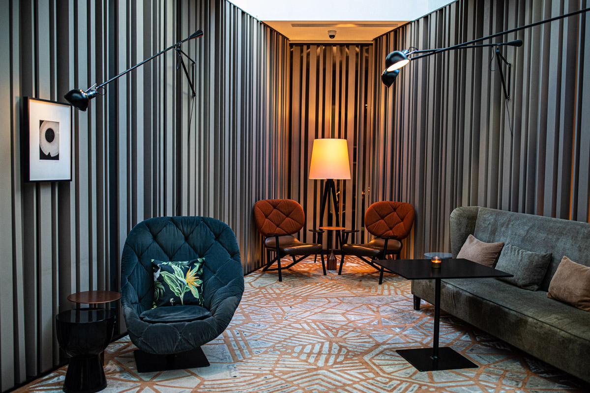 Accor at IHIF Berlin 2021 — Hospitality space Lounge seating and a floor lamp framed by vertical slatted walls at IHIF Berlin 2021