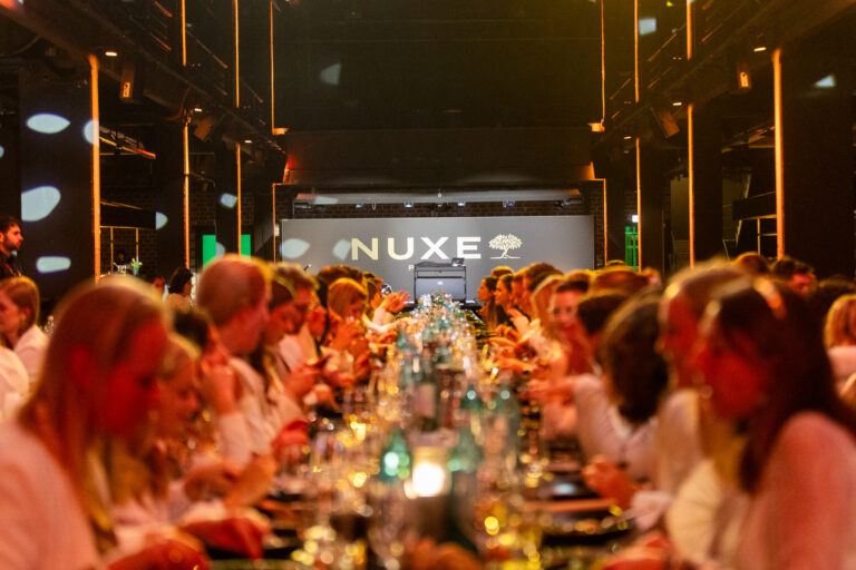 Dinner guests with NUXE branding in the background